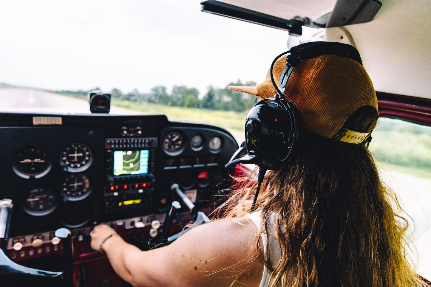 Pilot wearing a headset in a small cockpit checking instruments before takeoff