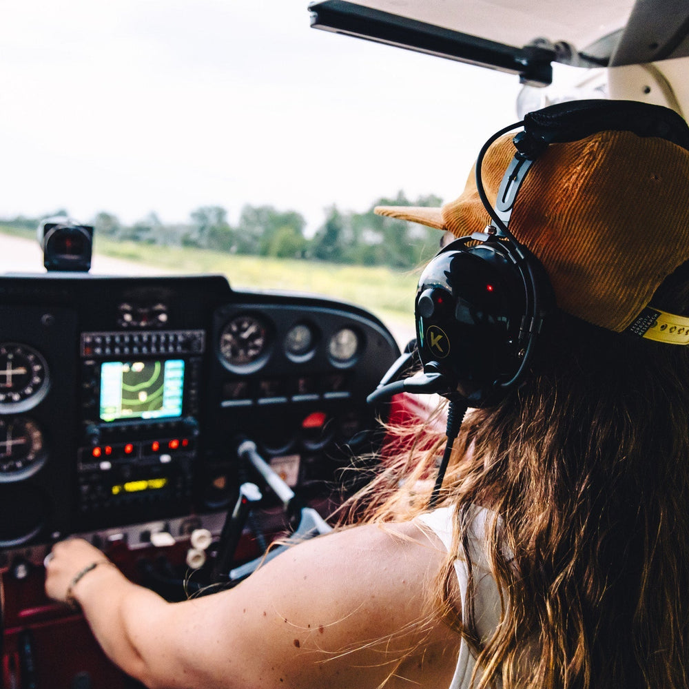 Pilot wearing a headset in a small cockpit checking instruments before takeoff